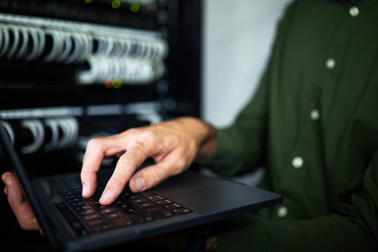 Technician managing hardware and software in a server room, emphasizing IT infrastructure and equipment maintenance