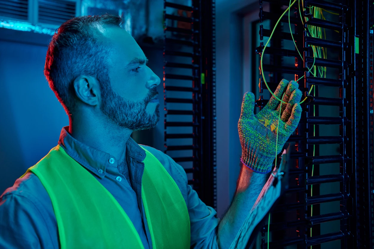 Technician organizing fiber optic cables in a server room, showcasing the installation and maintenance of Business Fibre networks